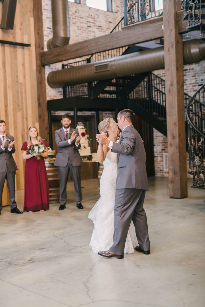Bride and Groom enjoy their first dance while the wedding party looks on