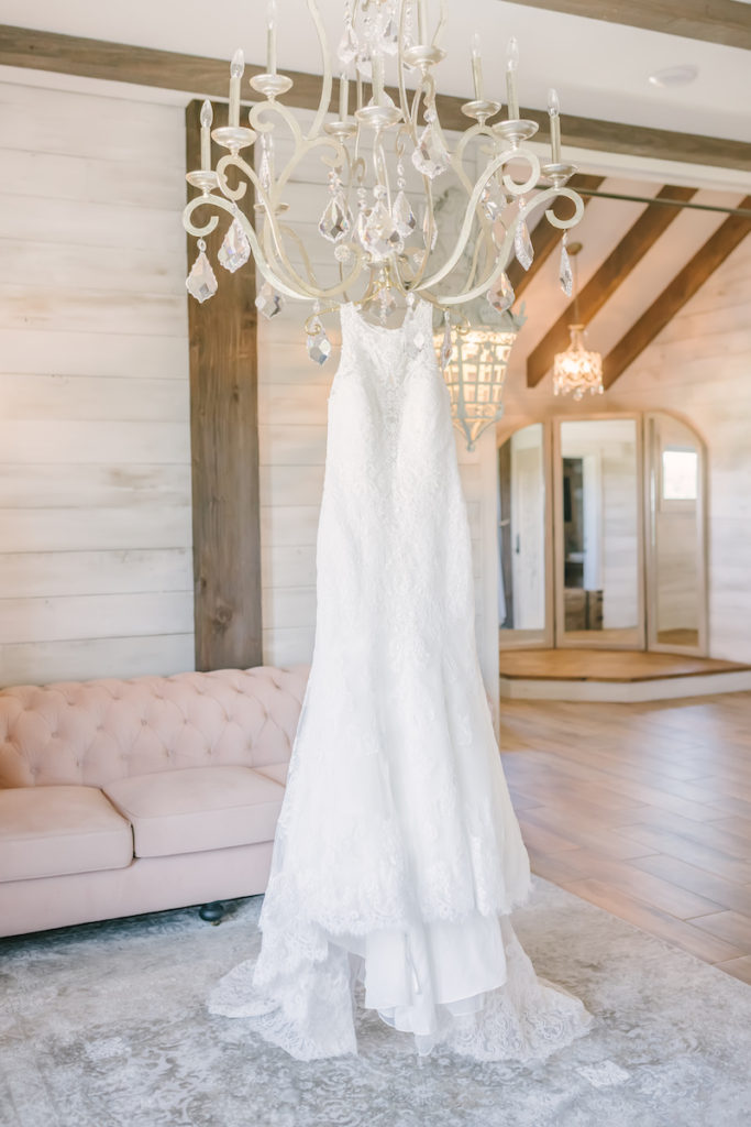 High neck lace gown by Brickhouse Bridal hangs from the crystal chandelier in the bridal suite