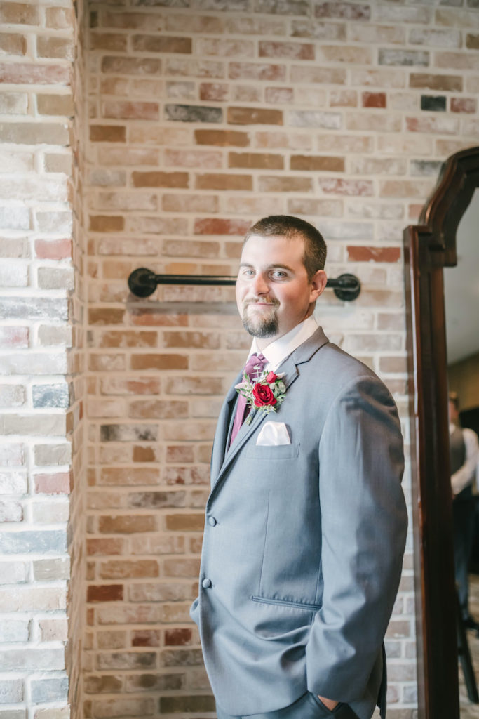 Groom smiles while getting ready in the groom suite at Weinberg at Wixon Valley Wedding Venue