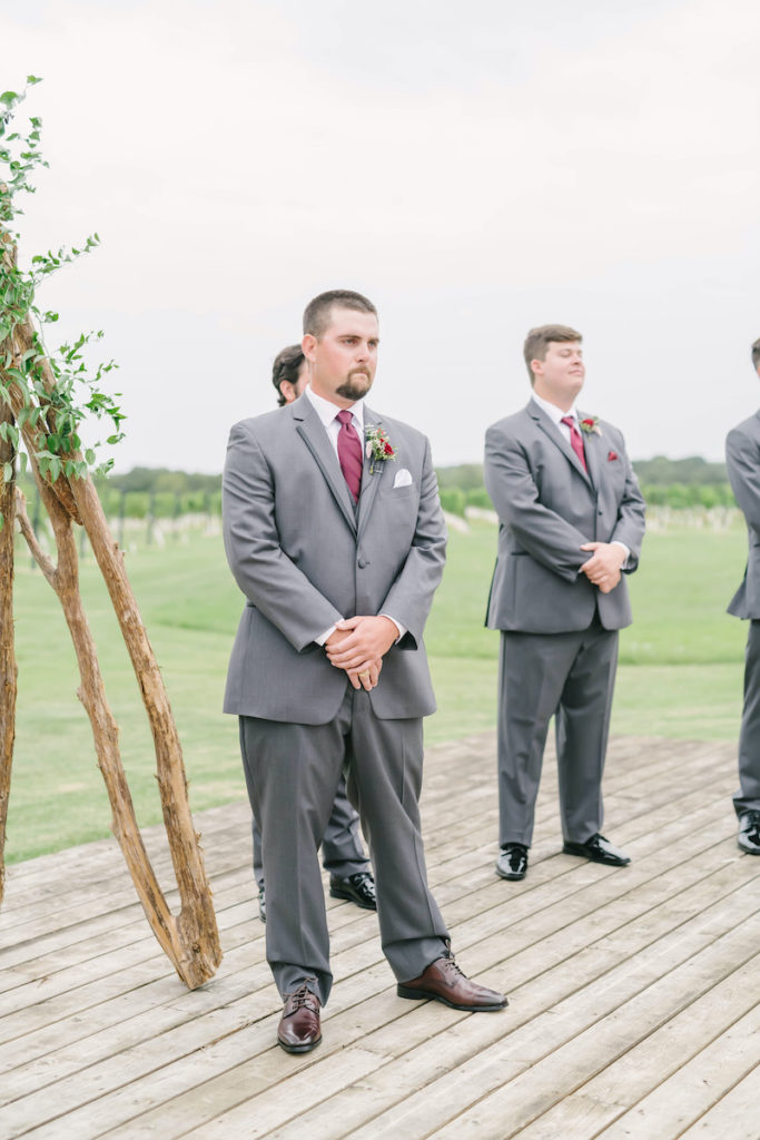 Groom tearily looks on as his bride walks down the isle to meet him under the floral arbor