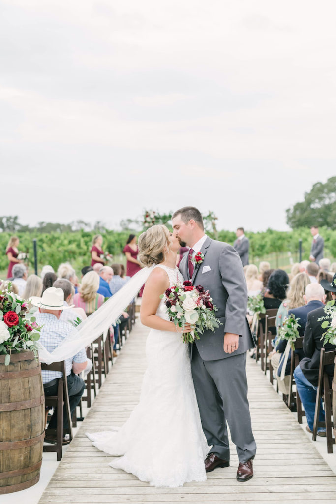 Bride and groom kiss as they are walking down the isle from the outdoor ceremony space