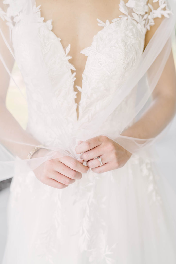 Detail shot of brides wedding dress in classic white with gorgeous detailed flowers sewn on in Alvin, TX by Christina Elliot Photography. wedding dress inspo classic wedding dress lace wedding dress hand sewn wedding dress hand stitched wedding dress sheer neckline vneck houston wedding photographer brazoria county bride formals wedding #houstontexasphotographer #alvintxweddingphotographer #texasweddingphotography #outdoorbridalformals #bridalphotography