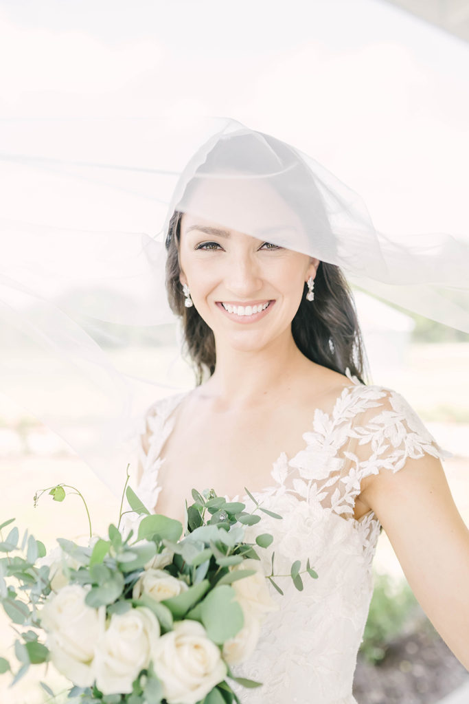 Beautiful bride with hanging diamond earrings and a long bridal veil that flows over her face in Alvin, TX by Christina Elliot Photography. wedding dress inspo brides wedding veil long wedding veils that go over face lace wedding dress sheer wedding dress still waters ranch event venue houston wedding photographer locations for bridal photoshoots in texas #houstontexasphotographer #alvintxweddingphotographer #texasweddingphotography #outdoorbridalformals #bridalphotography