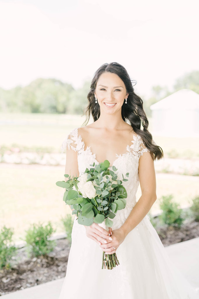 Gorgeous bride with simple bridal wedding bouquet with lots of leafy greens and a few simple white roses by Christina Elliot Photography in Alvin, TX. houston wedding photography bridals in texas simple wedding bouquet simple bouquet for bridals flowers for bridal photoshoot white and green bridal flowers still waters ranch event venue #houstontexasphotographer #alvintxweddingphotographer #texasweddingphotography #outdoorbridalformals #bridalphotography