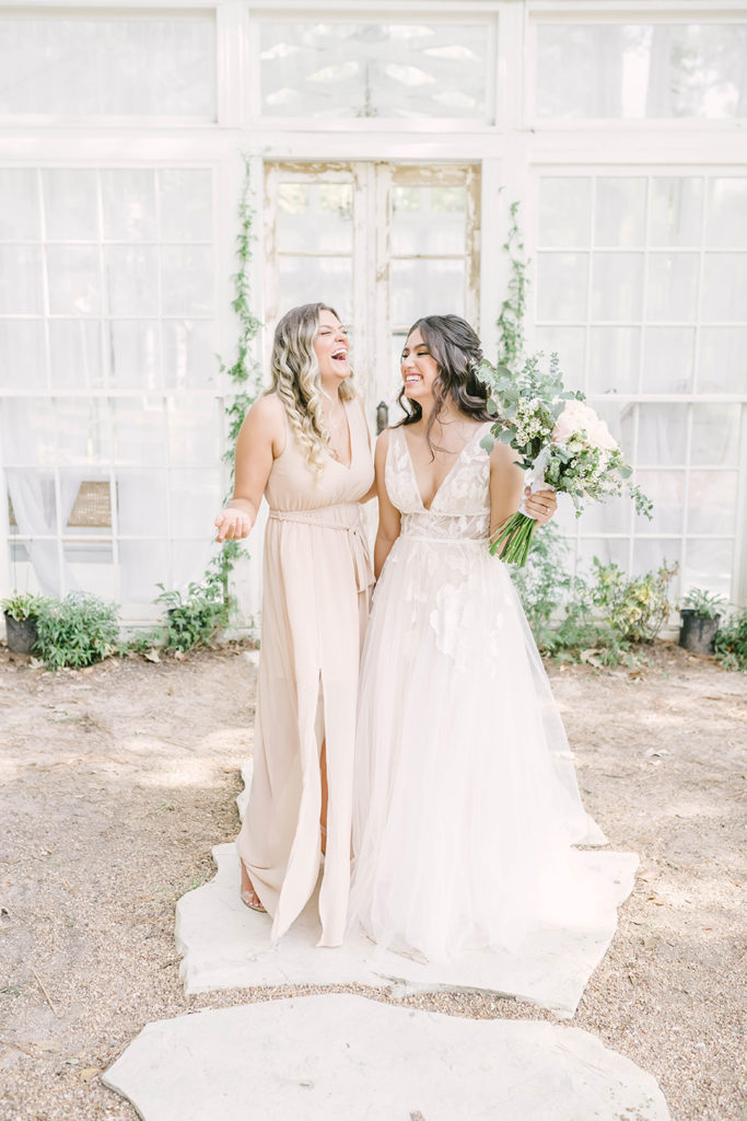 Beautiful bride in cream lace dress with bridesmaid in long simple silk cream wedding dress by Christina Elliot Photography in Houston, TX. bridesmaids what should my bridesmaids wear bridesmaids in cream dresses for bridesmaid silk dresses for wedding party lace wedding dress cream wedding dress tx greenhouse wedding woodlands tx #houstontexasphotographer #houstonweddingphotographer #texasweddingphotography #greenhousewedding #outdoorweddinginspo