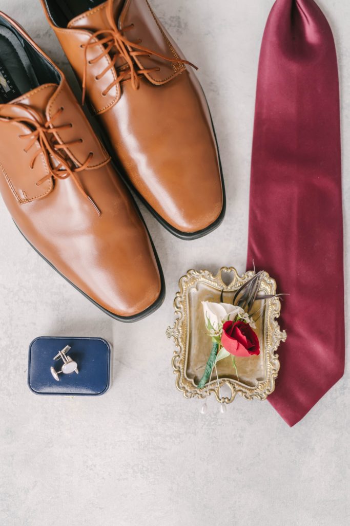 A stunning flatlay of details from the groom’s attire, including his shoes, tie, boutiennere, and cufflinks. Christina Elliott Photography wedding day flatlay detail shot groom’s attire houston wedding photography Butler’s courtyard wedding venue