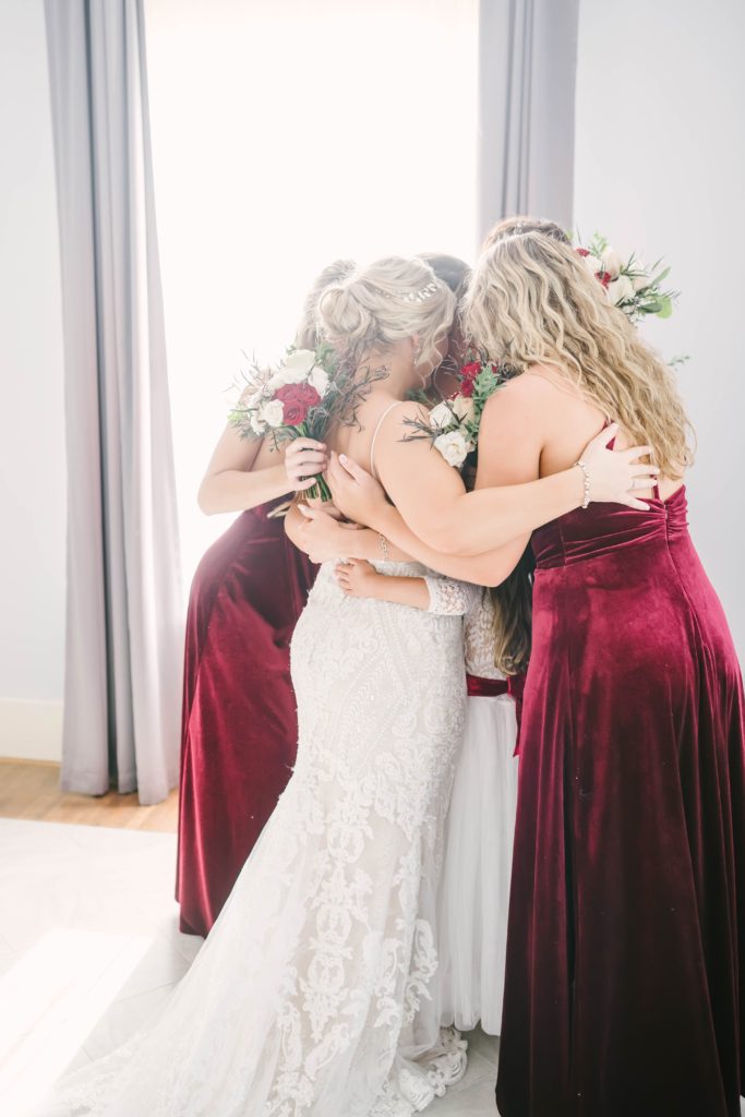 A candid shot of the bride and her bridesmaids taking a moment to give a group hug after getting ready on wedding day taken by Christina Elliot. Candid moments wedding day getting ready bridal party Butler’s Courtyard Houston Texas wedding venue inspo summertime