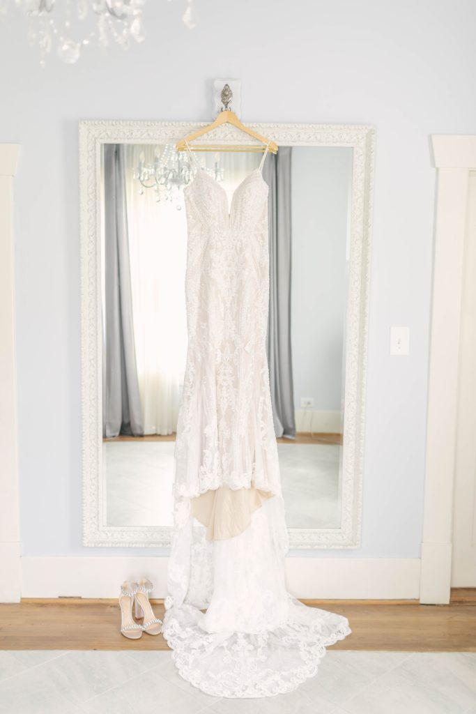 Beautiful beaded dress with long train hung over the white mirror in the bridal cottage at Butler's Courtyard Wedding Venue in league City, TX