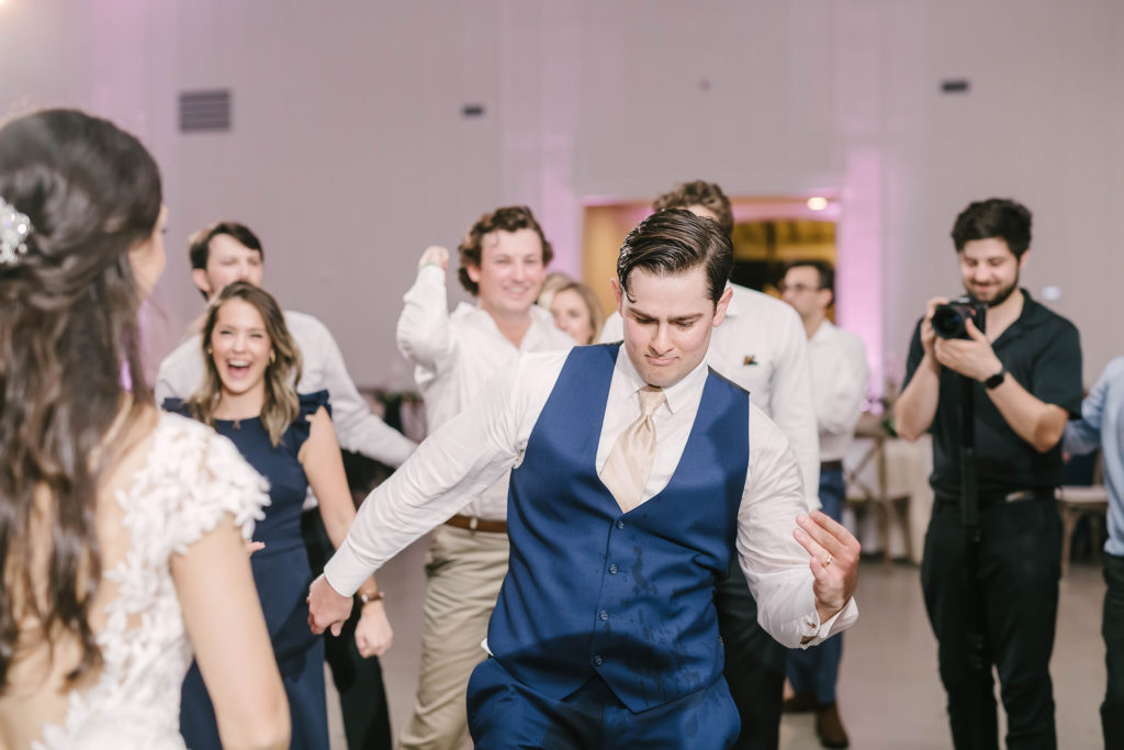 The groom shows off his dance moves in this beautiful barn style wedding in Alvin, Texas captured by Christina Elliot Photography. Still waters ranch wedding barn houston texas wedding photographer groom dance moves navy blue suit cream white tie dance party playful fun marriage candid details #houstonweddingphotographer #texasphotographer #weddingdaydetails #barnstylewedding #stillwatersranch #alvintexasphotographer #weddingday #brideandgroom #texanwedding #htxwedding #countrywedding
