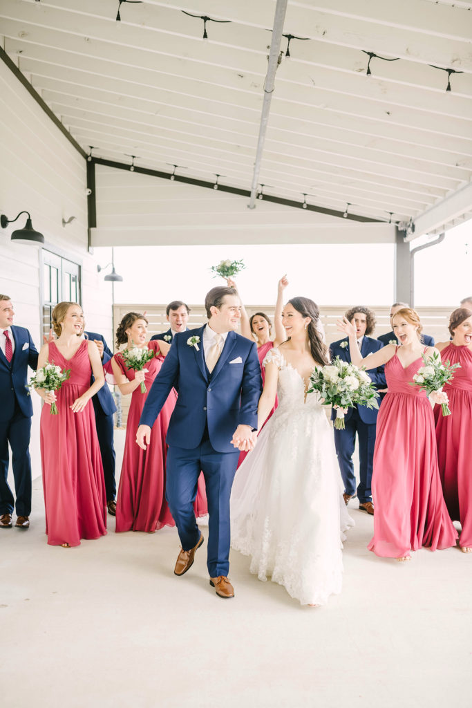 A fun candid moment of the bride and groom with their wedding party in Houston, Texas with Christina Elliot Photography. Candid moments wedding day bride and groom bridesmaids groomsmen pink bridesmaid dresses inspo wedding photographer marriage dance fun playful navy blue suits #houstonweddingphotographer #texasphotographer #weddingdaydetails #barnstylewedding #stillwatersranch #alvintexasphotographer #weddingday #brideandgroom #texanwedding #htxwedding #countrywedding