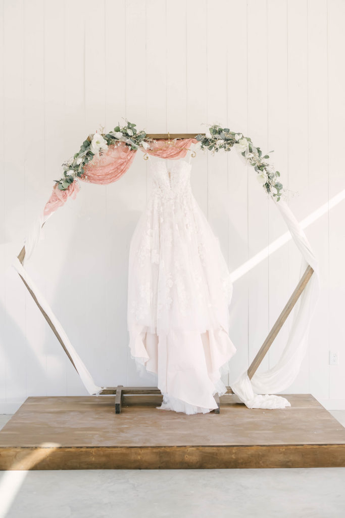 White lace dress hung from the hexagonal arbor at the ceremony site at the Barn at Willowynn open outdoor chapel.