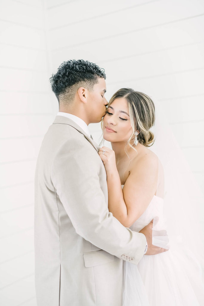 Newlywed couple pose for an intimate moment in the white shiplap chapel at the Farmhouse wedding venue.