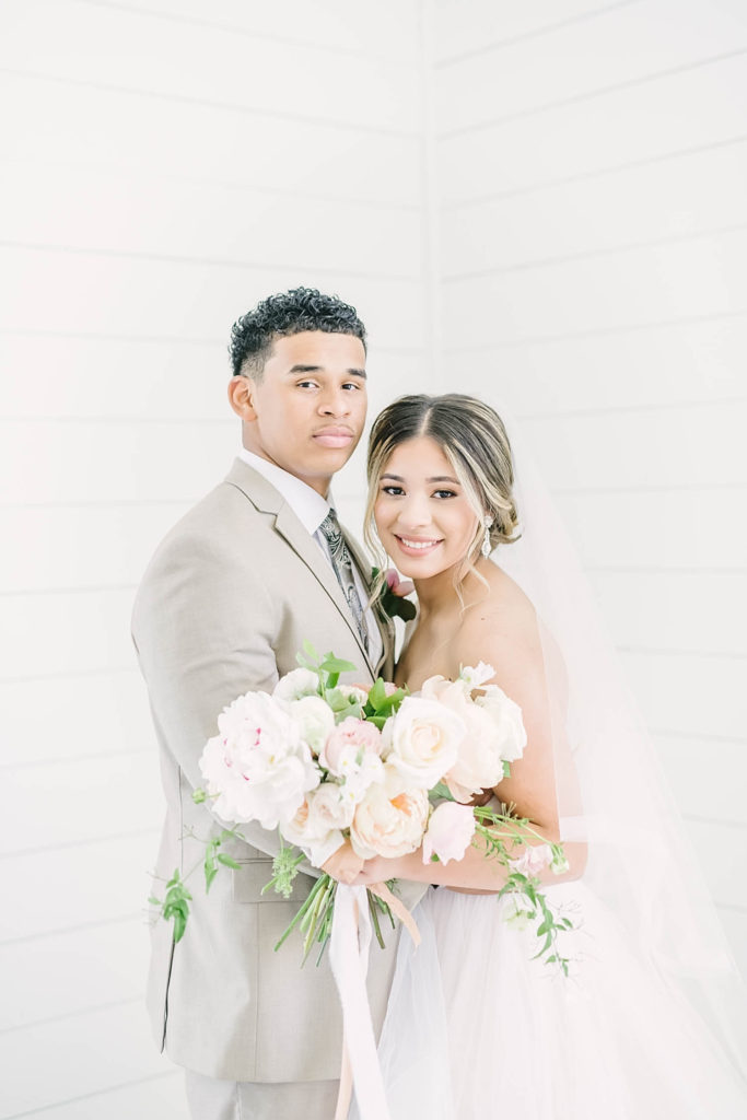 Newlywed couple pose for an intimate moment in the white shiplap chapel at the Farmhouse wedding venue.