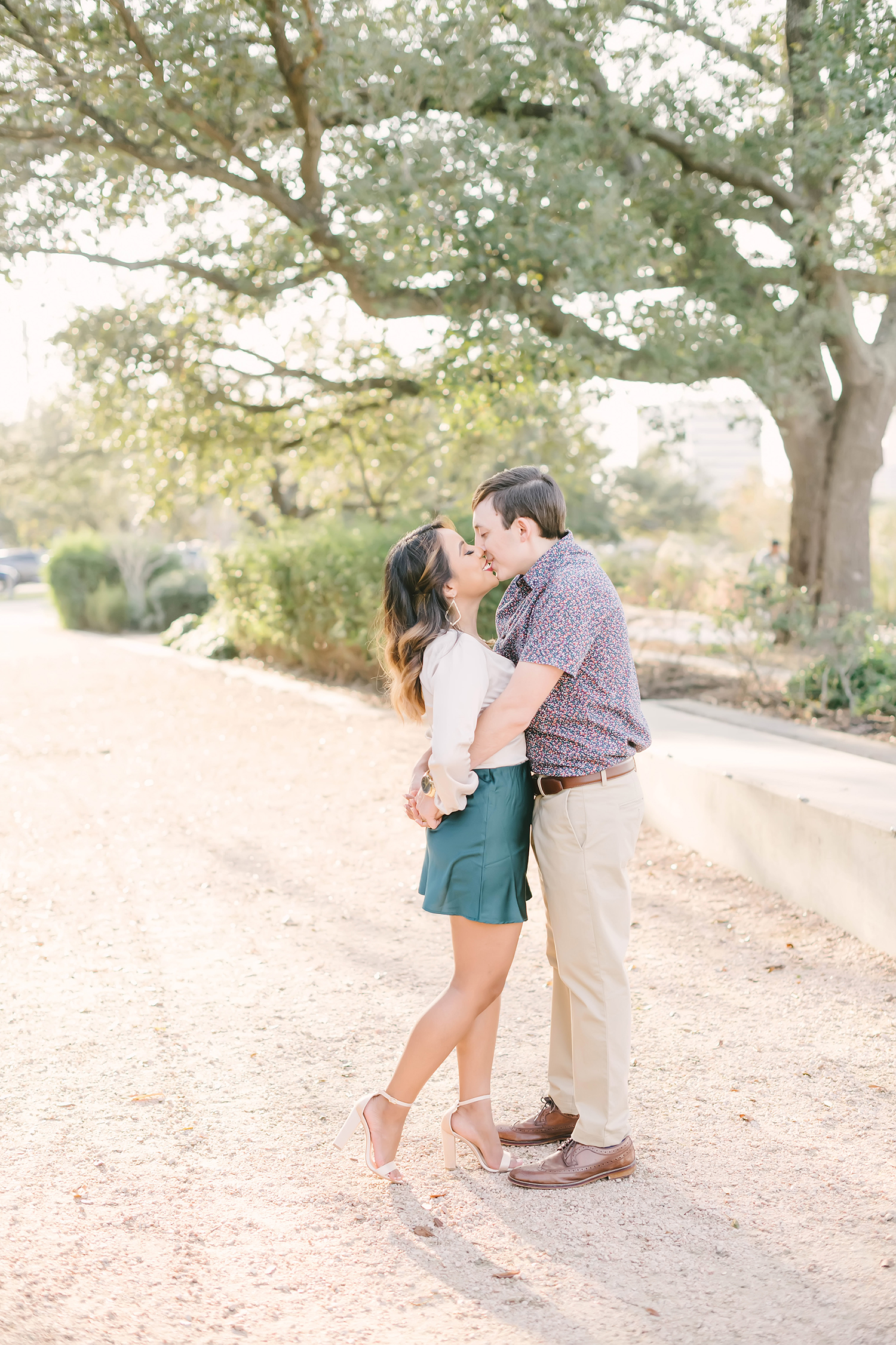 A beautiful springtime engagement session in Downtown Houston, Texas with Christina Elliot Photography. Kisses future bride and groom she said yes semi formal outfit wear inspo outdoor engagement shoot houston texas photographer white high heels teal skirt #christinaelliotphotography #houstonweddingphotographer #engagementpics #houstonphotographer #engagementphotos #shesaidyes #texasphotographer #photoinspiration #weddingphotography #houstonphotographer
