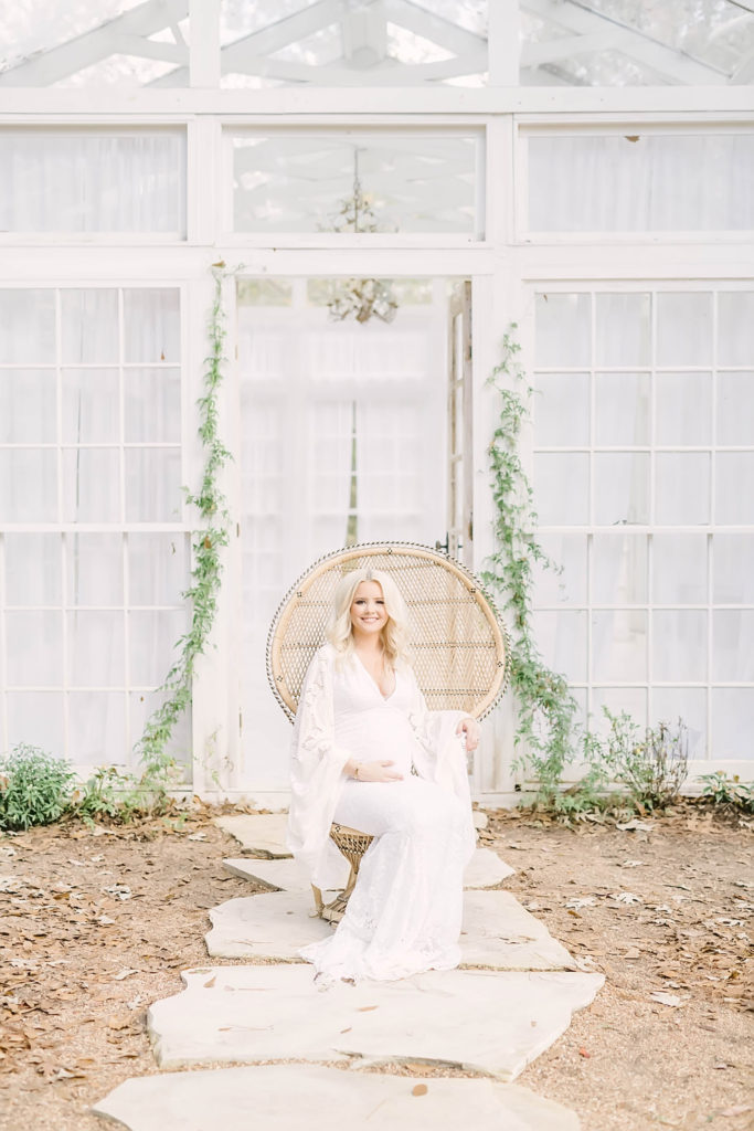 Stunning outdoor maternity session with a pregnant mother wearing a white lace dress sitting down in Conroe, Texas by Christina Elliott Photography. oak atelier photos green vine pregnancy background #christinaelliottphotography #christinaelliotmaternitysession #babybump #houstonmaternityphotographer #houstonmaternity #pregnancypic #houstonphotographylocations #materntiyoutfit #soontobeparents #babyontheway #houstonphotos #houstontexasmaternityphotographer #oakatelierphotos #conroetexas