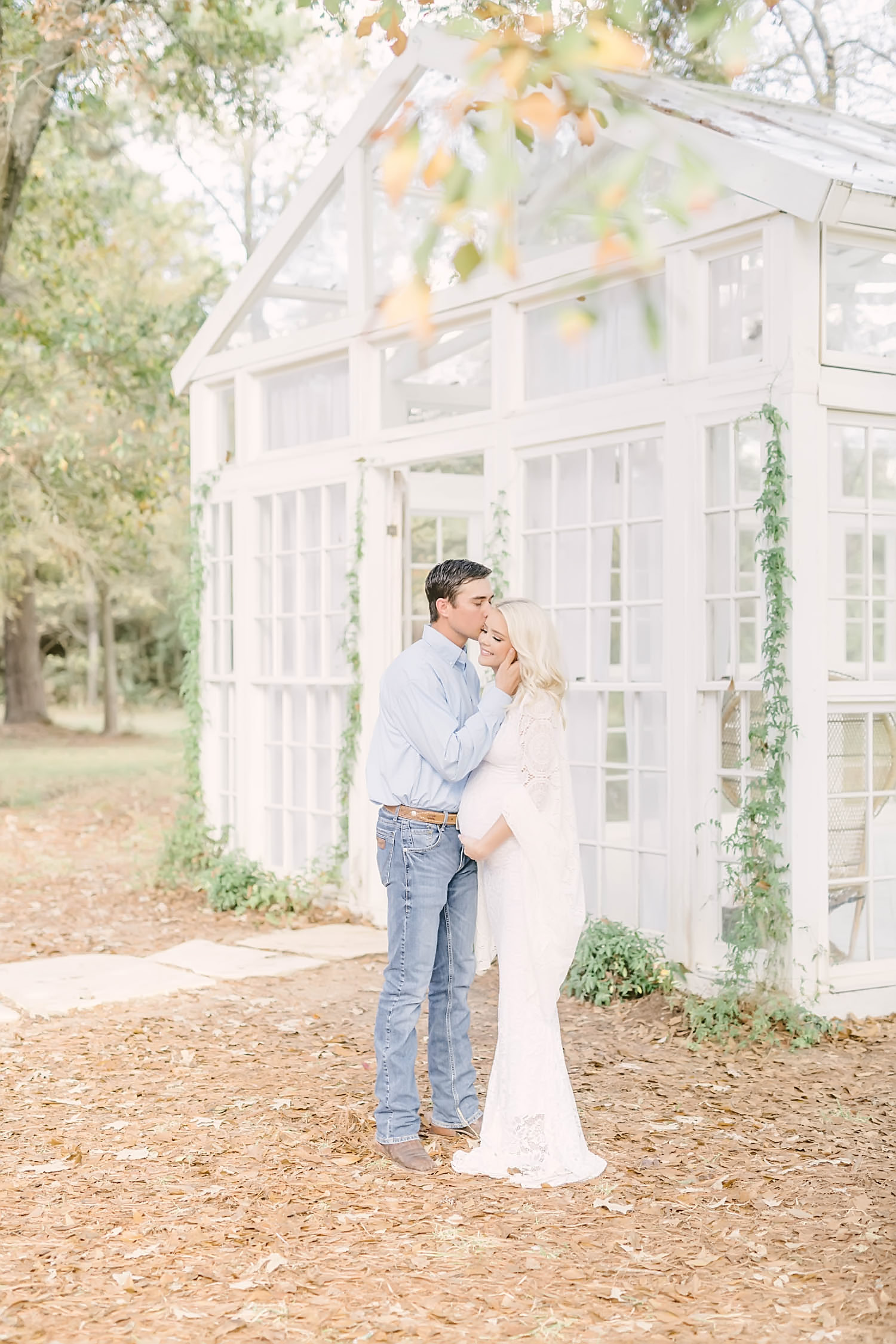 Husband kisses pregnant wife on forehead during maternity portrait session at the Oak Atelier by Chrisitna Elliott Photography in Conroe. White boho crochet floor length maternity dress fall maternity #christinaelliottphotography #christinaelliotmaternitysession #babybump #houstonmaternityphotographer #houstonmaternity #pregnancypic #houstonphotographylocations #materntiyoutfit #soontobeparents #babyontheway #houstonphotos #houstontexasmaternityphotographer #oakatelierphotos #conroetexas