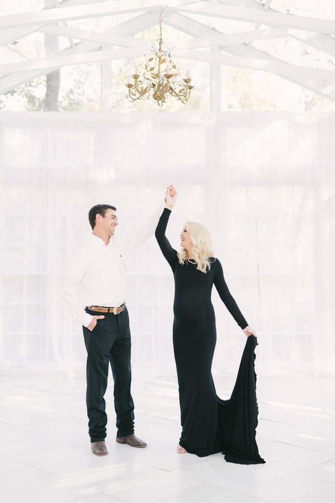 Christina Elliot Photography captures a couple dancing in a white pavilion at Oak Atelier in Conroe, Texas. cowboy husband dancing pic blonde woman baby bump preggo pregnancy diary #christinaelliottphotography #christinaelliotmaternitysession #babybump #houstonmaternityphotographer #houstonmaternity #pregnancypic #houstonphotographylocations #materntiyoutfit #soontobeparents #babyontheway #houstonphotos #houstontexasmaternityphotographer #oakatelierphotos #conroetexas
