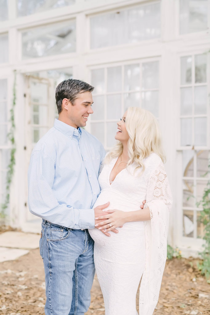 Mom and dad laugh during their maternity portrait session at the Oak Atelier by Christina Elliott Photography. laughing mom and dad first child first baby new parents #christinaelliottphotography #christinaelliotmaternitysession #babybump #houstonmaternityphotographer #houstonmaternity #pregnancypic #houstonphotographylocations #materntiyoutfit #soontobeparents #babyontheway #houstonphotos #houstontexasmaternityphotographer #oakatelierphotos #conroetexas