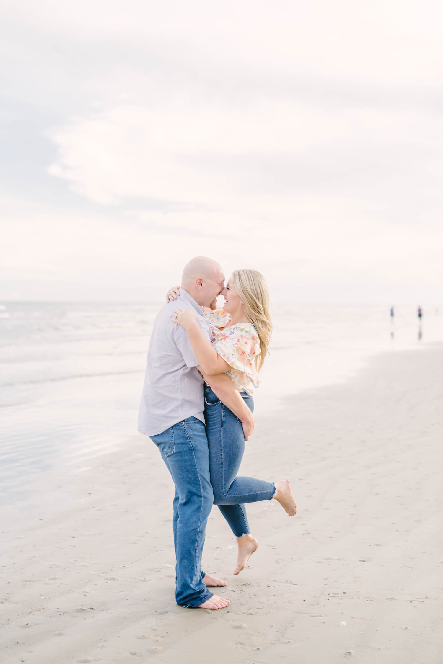 Galveston engagement portraits with couple laughing and kissing on the beach during sunset.