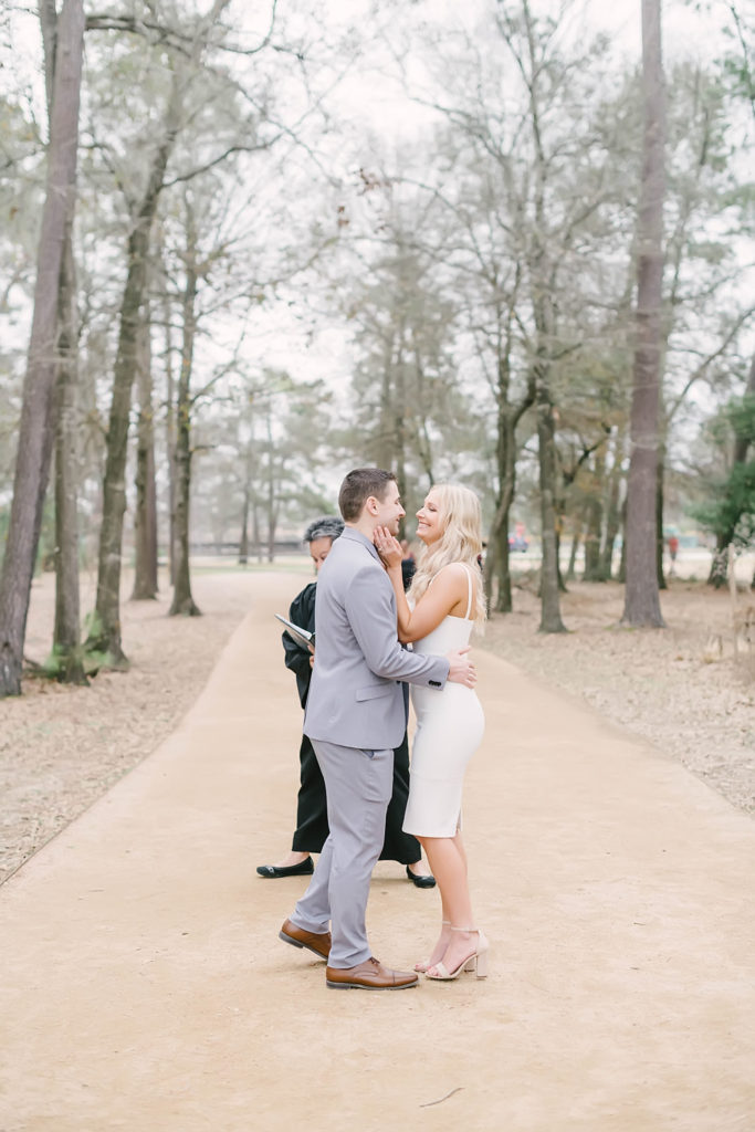 Newlyweds joyfully kiss on the gravel pathway in Memorial Park Eastern Glades after their intimate wedding ceremony. Houston elopement photographer. Houston wedding photographer.