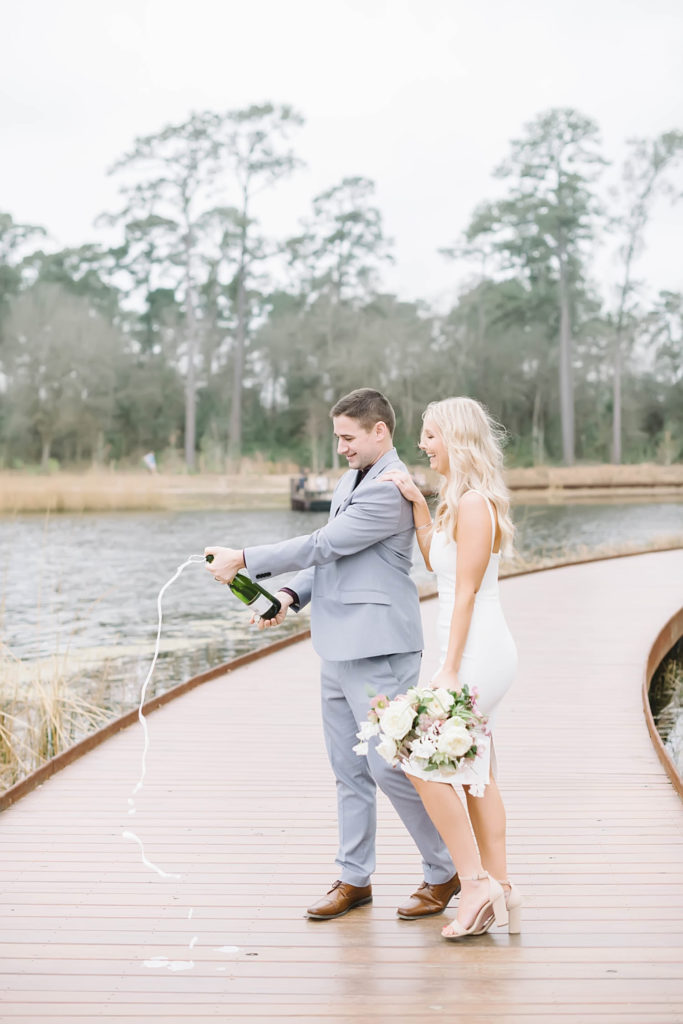 Bride and groom celebrate by popping champagne after their intimate wedding ceremony at Memorial Park with Christina Elliott Photography. Houston wedding photographer.