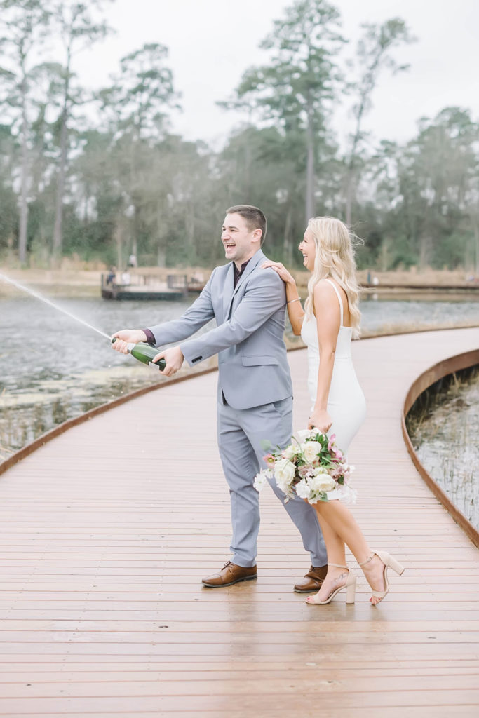 Bride and groom celebrate by popping champagne after their intimate wedding ceremony at Memorial Park with Christina Elliott Photography. Houston wedding photographer.