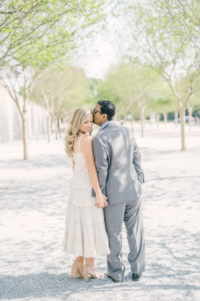 Groom kisses his bride on her head during their engagement portrait session at McGovern Centennial Gardens in with Houston wedding photographer Christina Elliott Photography.