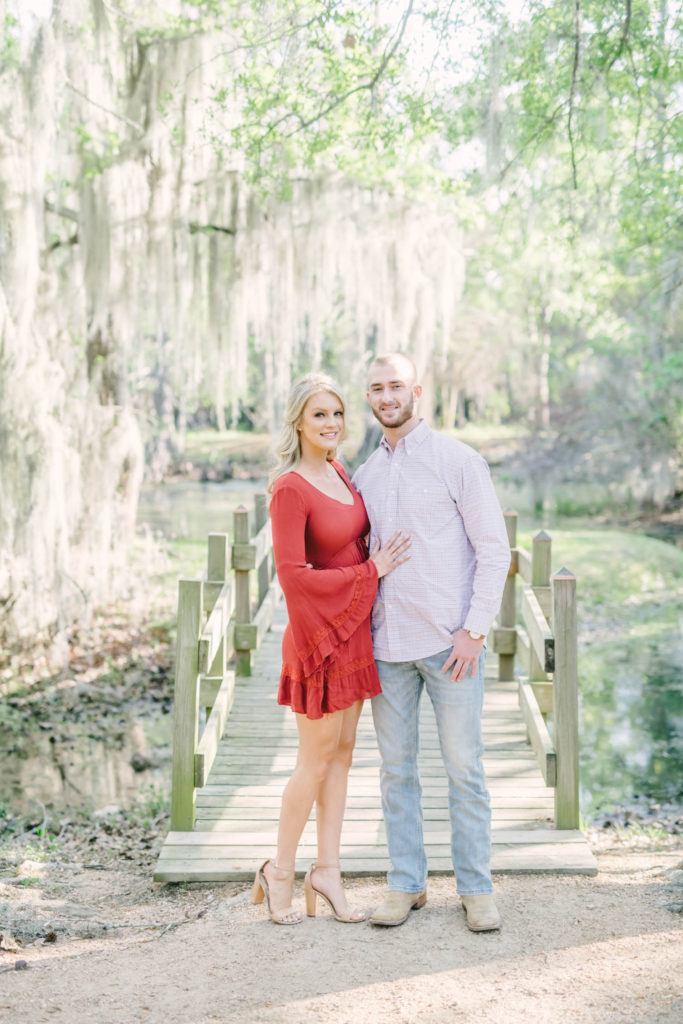 Couple pose in front of bridge with hanging spanish moss for their cypress engagement session.