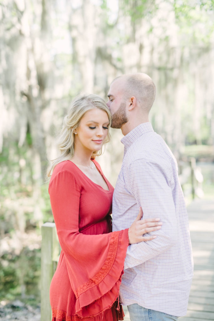 Groom kisses his bride to be's forehead during their engagement portrait session at Cypress Hope for their engagement portrait session.