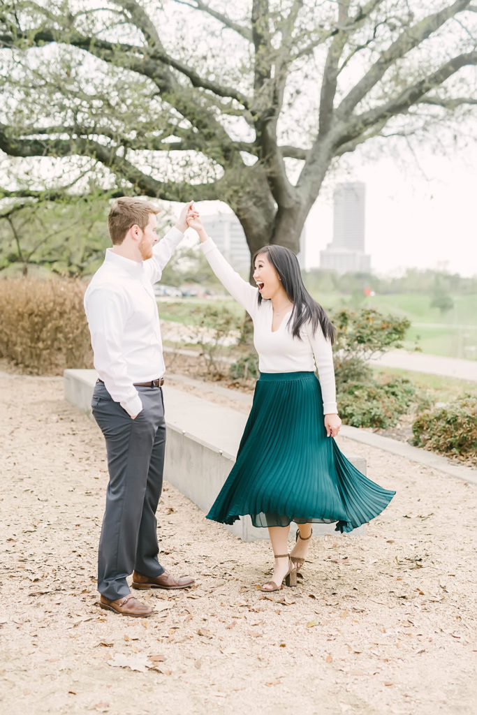 Couple laughing and dancing during their Downtown Houston engagement session at Eleanor Tinsley Park.
