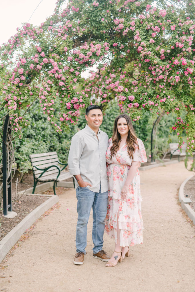 Couple playfully poses in front of the crawling roses at McGovern Centennial Gardens with Houston wedding photographer Christina Elliott Photography.