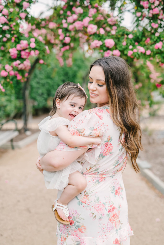 Smiling baby girl plays with her mom in the Rose Gardens at McGovern Centennial Gardens in Houston with Houston wedding photographer Christina Elliott Photography.