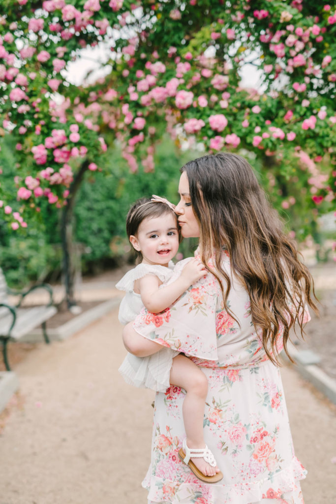 Smiling baby girl plays with her mom in the Rose Gardens at McGovern Centennial Gardens in Houston with Houston wedding photographer Christina Elliott Photography.