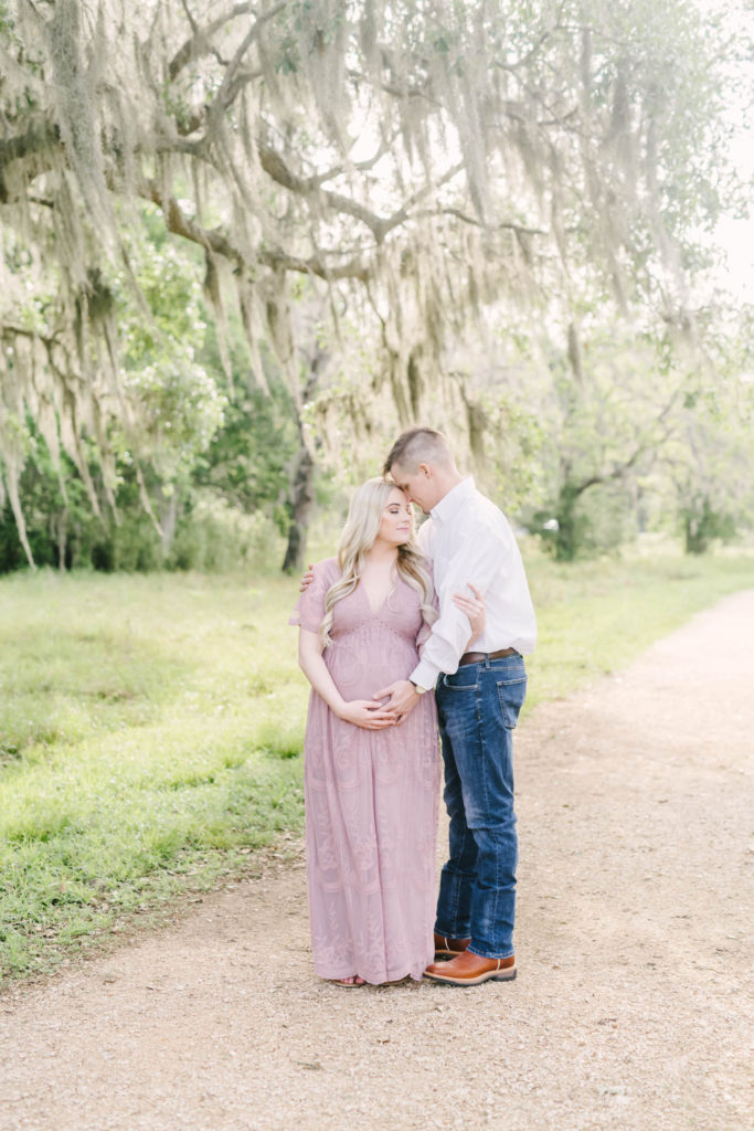 Couple snuggles together for their morning maternity session at Brazos Bend State Park with Christina Elliott Photography, Houston maternity photographer. outdoor maternity session bright and natural editing texas photography #christinaeliottphotography #christinaelliotmaternity #brazosbendstatepark #houstonmaternityphotographer #parentstobe #babybumppicutes #houstonareaphotographer #professionalmaternityphotographer #houstonmaternity #preggo #pregnancyjournal #texasmaternityphotographer