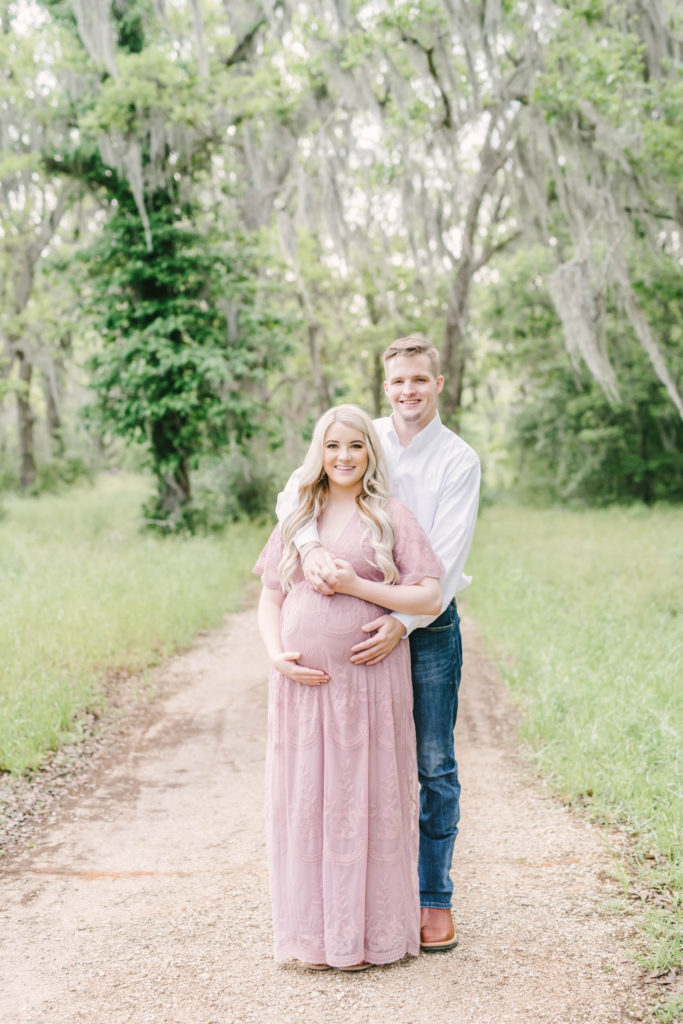 Christina Elliott Photography captures a husband holding his pregnant wife in Brazos Bend State Park during a maternity session. maternity session inspiration sweet child of mine white button down #christinaeliottphotography #christinaelliotmaternity #brazosbendstatepark #houstonmaternityphotographer #parentstobe #babybumpicutes #houstonareaphotographer #professionalmaternityphotographer #houstonmaternity #preggo #pregnancyjournal #texasmaternityphotographer