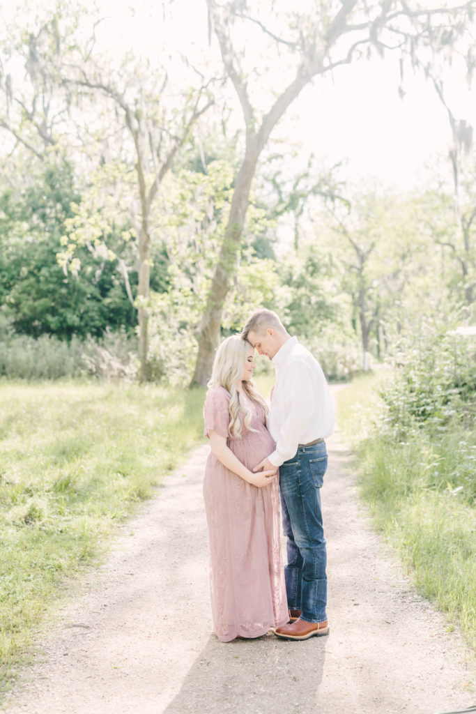 In Houston, Texas on a gravel country road mother and father to be hold hands together taken by Christina Elliott Photography. Mother to be mothers to be holding hands pose maternity fashion #christinaeliottphotography #christinaelliotmaternity #brazosbendstatepark #houstonmaternityphotographer #parentstobe #babybumpicutes #houstonareaphotographer #professionalmaternityphotographer #houstonmaternity #preggo #pregnancyjournal #texasmaternityphotographer