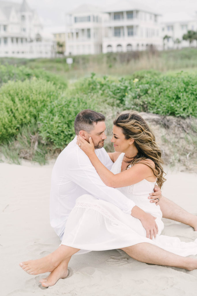Couple sit on sandy beach during their Galveston Island beach engagement session with Houston wedding photographer Christina Elliott Photography.