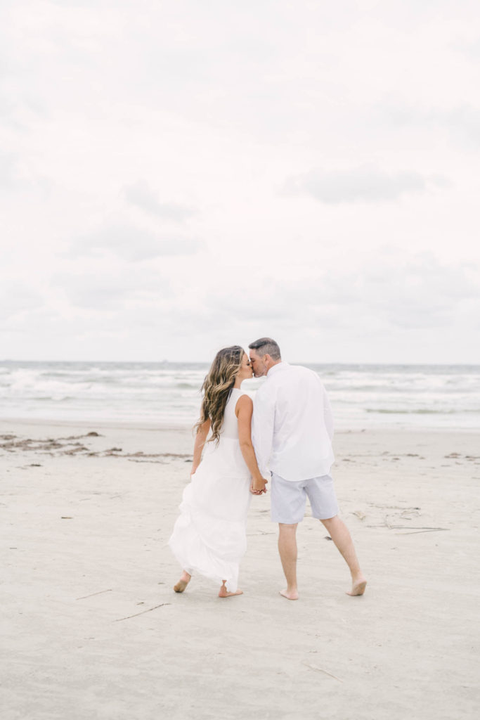 Couple stop during their walk on the beach to grab a quick kiss during their Galveston Island engagement session.