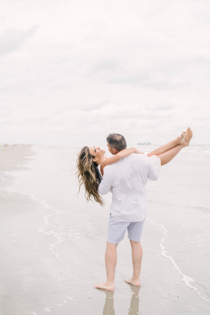 Husband dips wife on beach during their playful beach engagement session on Galveston Island in the Beachtown neighborhood with Galveston wedding photographer Christina Elliott Photography.