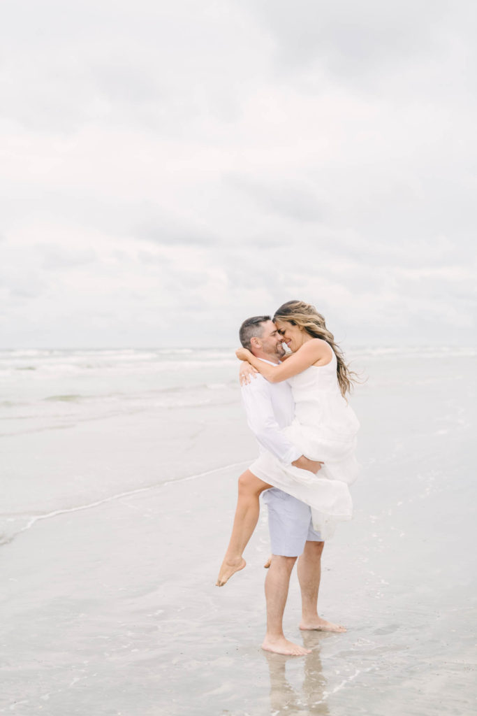 Couple kisses on the beach during their summer beach engagement session with Galveston wedding photographer Christina Elliott Photography.