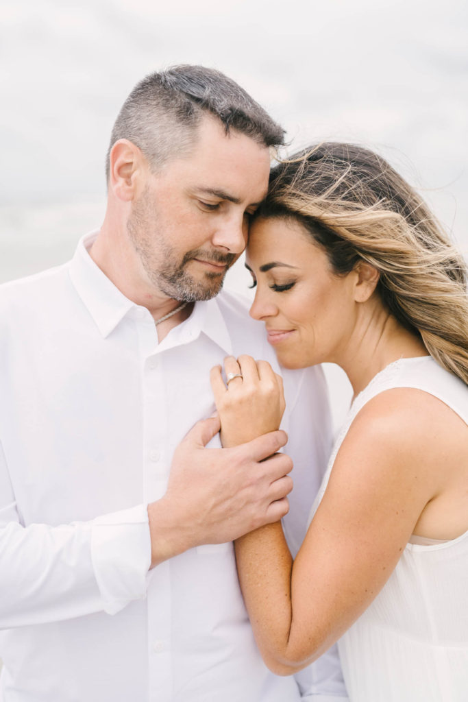 Couple snuggles in during their beach engagement session with Galveston wedding photographer CHristina Elliott Photography.