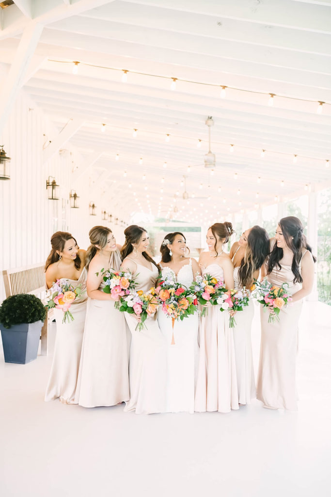 Christina Elliot Photography in Texas shows a beautiful bride with the wedding party in matching white dresses. how to dress bridal party best colors for bridal party bridal party gifts how to dress your bridal party matching outfits for bridal party pajamas for bridesmaids getting ready photos for wedding texas wedding photographer how to plan your wedding #texasweddingphotographer #farmhousewedding #farmhouseweddinginspo #texasphotographer #farmhouseweddingdecor #texasweddinglocations