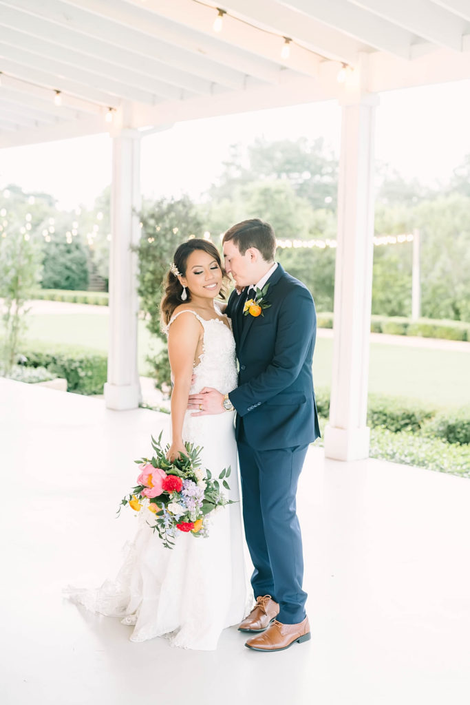 Happy couple with a gorgeous class white dress and navy blue suit by Christina Elliot Photography in Texas. poses for bride and groom summer wedding outfits for bride and groom poses for bride and groom classic wedding dress for bride classic suit for groom summer outfits for wedding white barn wedding #texasweddingphotographer #farmhousewedding #farmhouseweddinginspo #texasphotographer #farmhouseweddingdecor #texasweddinglocations