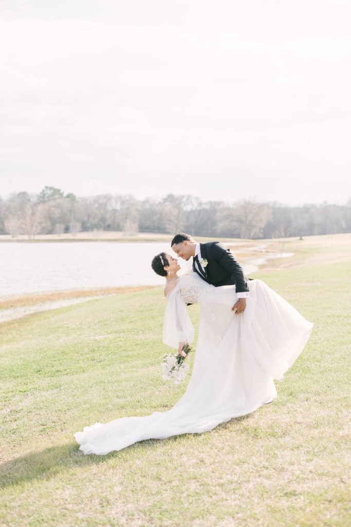 Groom dips his bride and goes in for a kiss in front of a farmhouse pond during a Houston wedding by Christina Elliott Photography. groom dips bride wedding pose inspiration Houston weddings tie the knot outdoor wedding photography #christinaelliottphotography #christinaelliottweddings #TheFarmhouseMontgomery #farmhouseweddings #texasweddings #houstonweddingphotographers #mrandmrs #tildeathdowepart #weddingphotography #tietheknot #Houstonweddings #weddinginspiration #bride #groom
