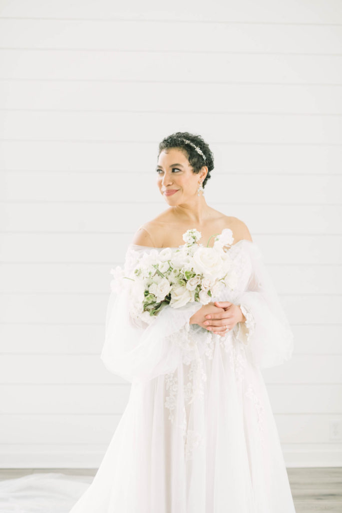 Stunning bride with short dark hair, off-the shoulder sweetheart neckline gown and white wedding bouquet smiles with her mouth closed the day of her wedding in Houston by Christina Elliott Photography. sweetheart neckline wedding day #christinaelliottphotography #christinaelliottweddings #TheFarmhouseMontgomery #farmhouseweddings #texasweddings #houstonweddingphotographers #mrandmrs #tildeathdowepart #weddingphotography #tietheknot #Houstonweddings #weddinginspiration #bride #groom