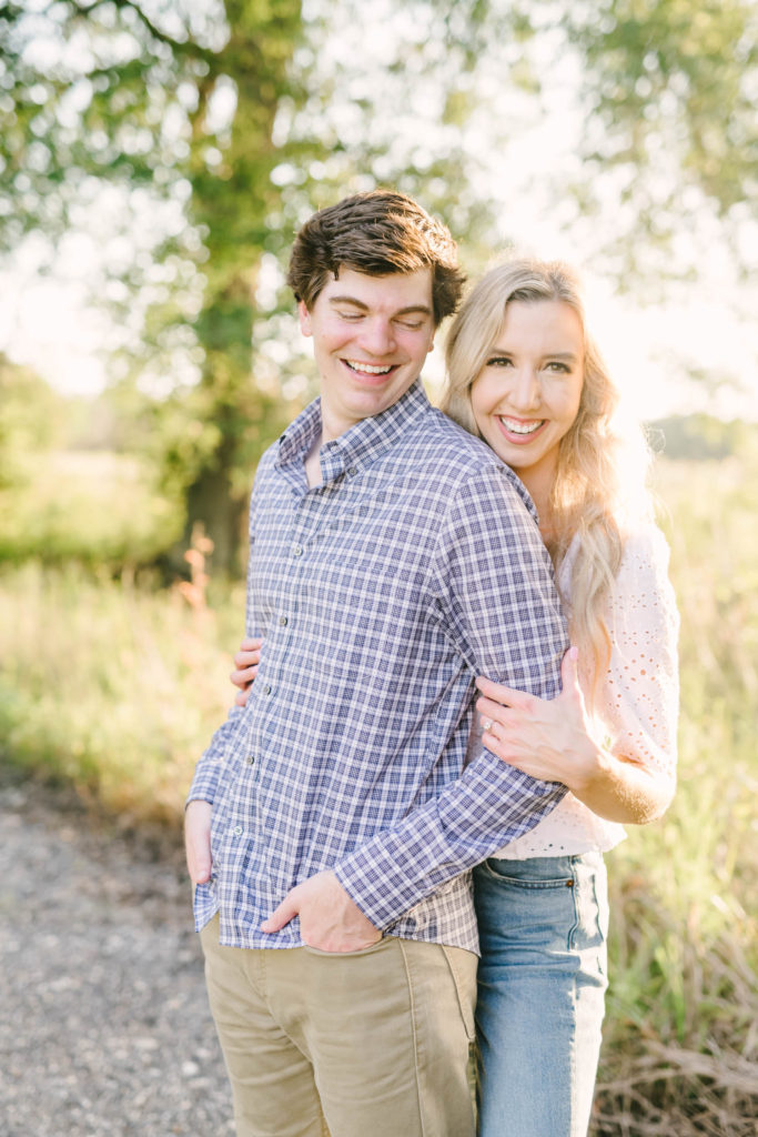 On a warm sunny day in Houston, Texas a couple smiles during sunset during an engagement portrait with Christina Elliott Photography. blue plaid button-down shirt tan pants white shirt and jeans outfit #christinaelliottphotography #christinaelliottengagements #houstonengagements #brazosbendstateparkengagements #brazosbendphotography #houstonengagementphotographer #weddingannoucementphotos #houstonphotographers #couplegoals #soontobemarried #engaged #engagementphotos