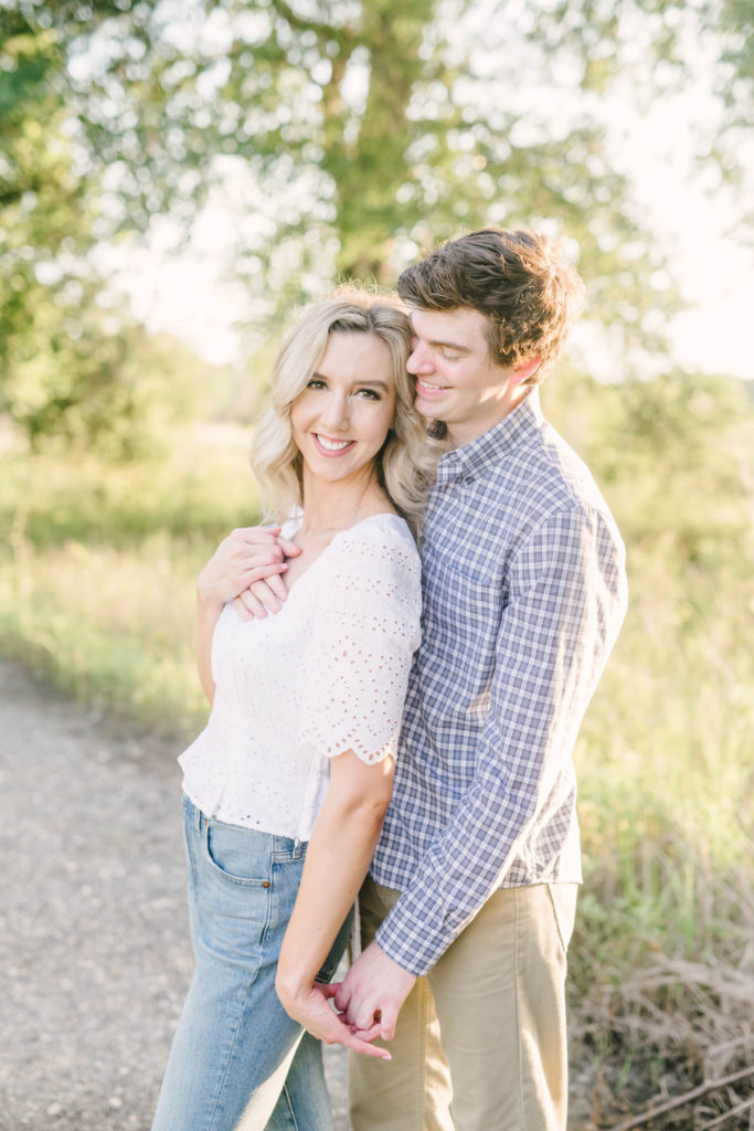 During an engagement session in Houston, Texas a couple leans together and holds hands while standing on a gravel road by Christina Elliott Photography. texas engagements engagement poses young love soon to be married #christinaelliottphotography #christinaelliottengagements #houstonengagements #brazosbendstateparkengagements #brazosbendphotography #houstonengagementphotographer #weddingannoucementphotos #houstonphotographers #couplegoals #soontobemarried #engaged #engagementphotos