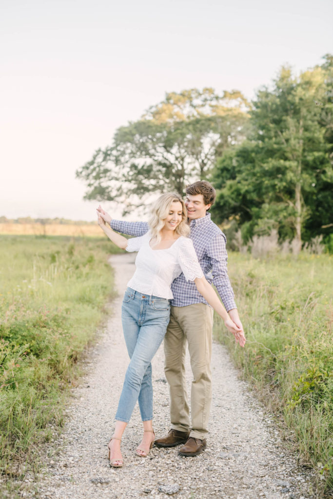 At Brazos Bend State Park a couple holds hands and swings in and out during sunset with cute casual engagement attire with Christina Elliott Photography. couple poses wedding photographers engagement outfit ideas #christinaelliottphotography #christinaelliottengagements #houstonengagements #brazosbendstateparkengagements #brazosbendphotography #houstonengagementphotographer #weddingannoucementphotos #houstonphotographers #couplegoals #soontobemarried #engaged #engagementphotos