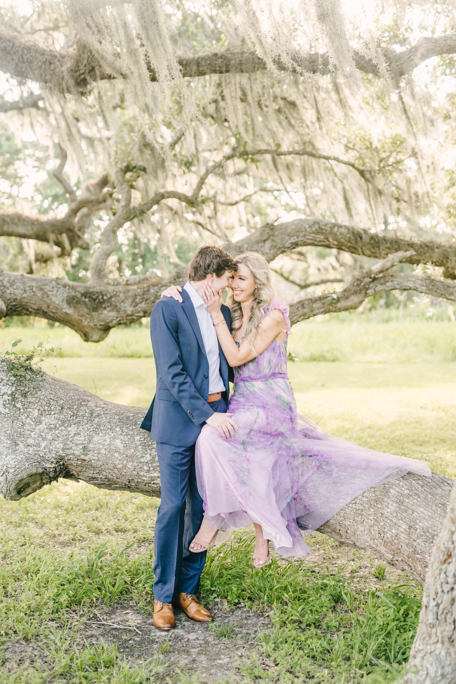 In Houston, Texas a darling couple goes in for a kiss as a woman sits on a tree branch and holds her fiance's jaw by Christina Elliott Photography. fiance photography wedding announcement pictures darling couple in love #christinaelliottphotography #christinaelliottengagements #houstonengagements #brazosbendstateparkengagements #brazosbendphotography #houstonengagementphotographer #weddingannoucementphotos #houstonphotographers #couplegoals #soontobemarried #engaged #engagementphotos