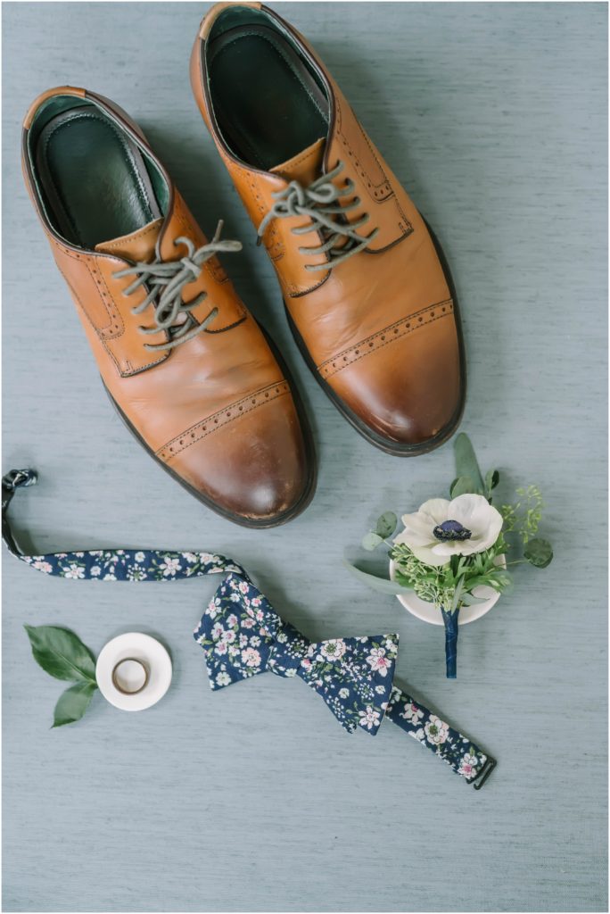 Groom flat lay photo featuring brown dress shoes navy blue floral bow tie floral boutineer and wedding ring by Christina Elliott Photography a Houston wedding photographer. groom flat lay brown shoes navy blue bowtie #christinaelliottphotography #christinaelliottweddings #Winerywedding #Houstonweddings #newlyweds #weddingdress #weddingphotography #Houstonweddingphotographers #dreamyweddings #bluesuit #weddingstyle #mrandmrs #weddinggoals #Houstonphotographers